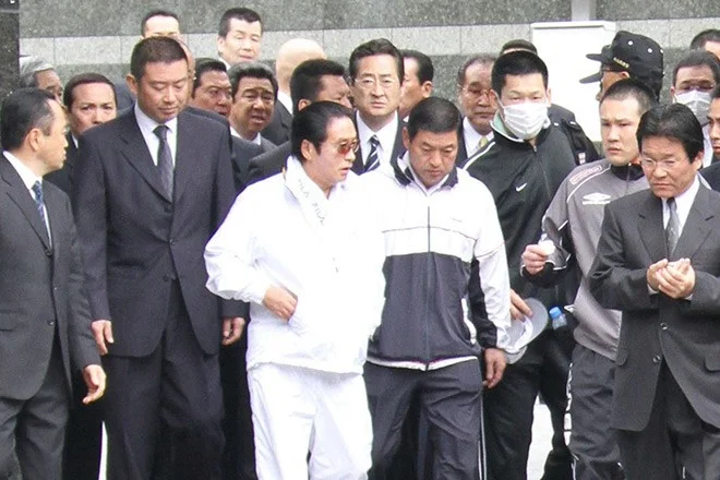 Satoru Nomura, left centre, goes outside during a house search conducted by Fukuoka prefectural police on April 10, 2010, in Kita Kyushu's Kokura-Kita Ward.