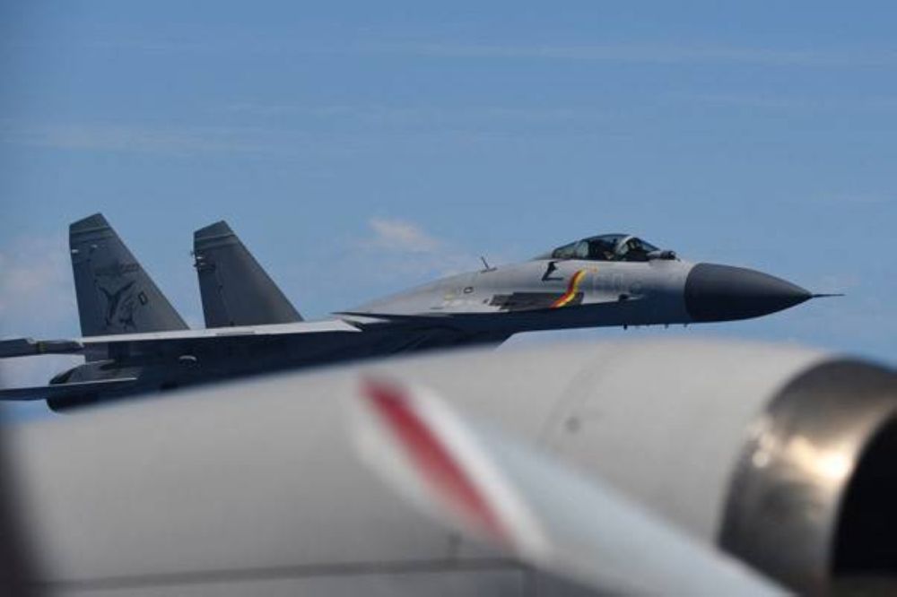 A Chinese J-15 fighter jet flies close to a JMDF P-3C