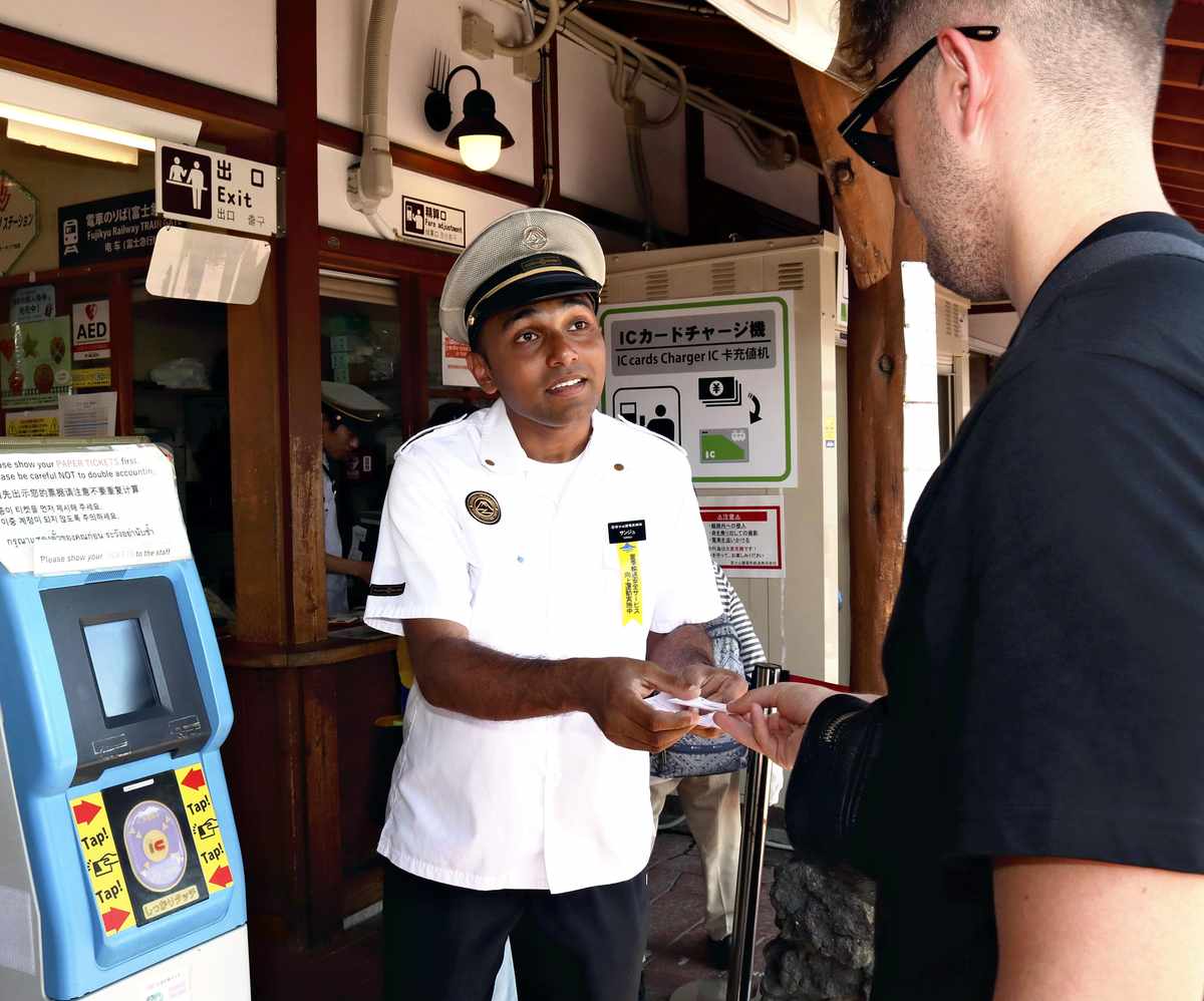 Sanju Ekanayake, a Sri Lankan-born station attendant, helps a foreign tourist at Kawaguchiko Station in Yamanashi Prefecture